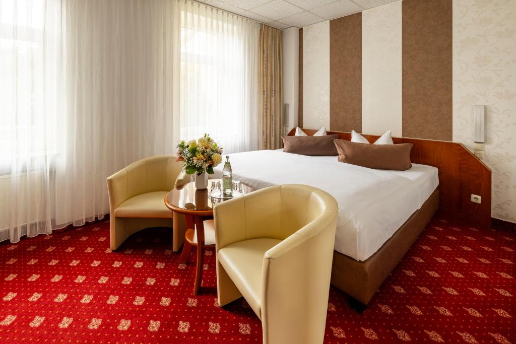 ein Hotelzimmer mit einem Bett, einem Tisch und Stühlen in der Unterkunft Hotel Berlin in Leipzig