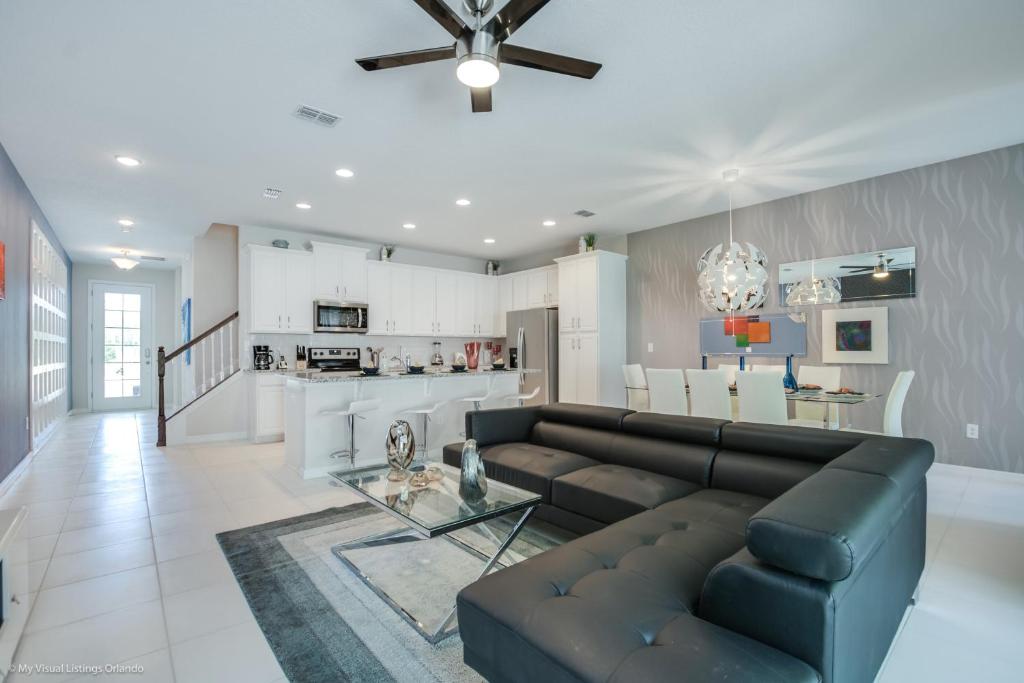 ein Wohnzimmer mit einem schwarzen Sofa und einer Küche in der Unterkunft Solara Resort - 5 Bed 4,5 Baths TOWNHOME in Orlando