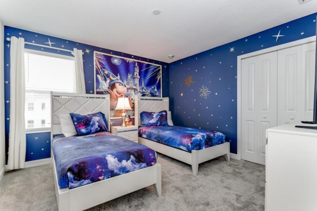 a bedroom with two beds and a blue wall at Storey Lake Resort - 9 Bed 5 Baths VILLA in Kissimmee