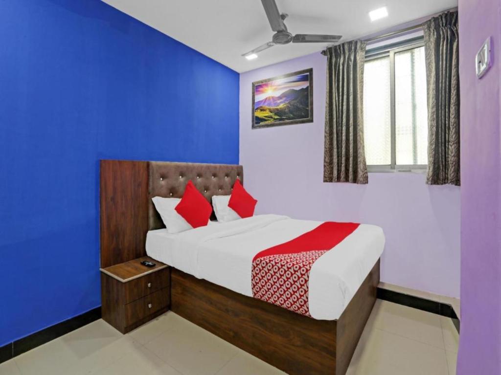 a bedroom with a bed with blue walls and red pillows at Hotel Welcome Inn,Mumbai in Mumbai
