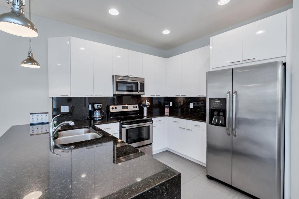 een keuken met witte kasten en een roestvrijstalen koelkast bij Serenity - 3 Bed 3 Baths TOWNHOME in Orlando