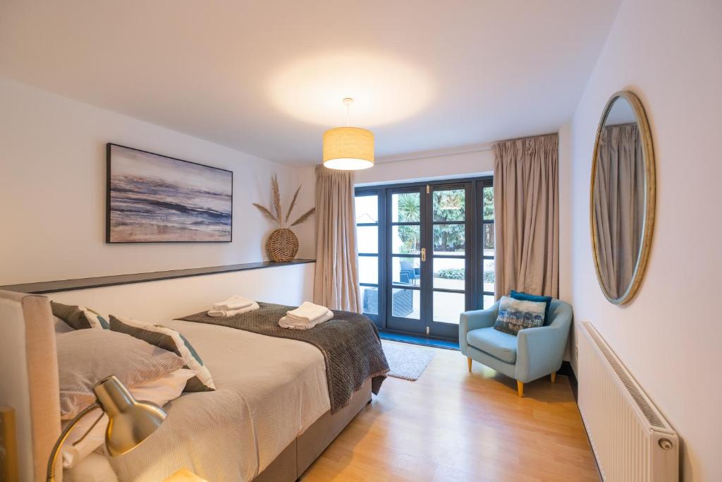 um quarto com uma cama e uma cadeira azul em Modern apt near gardens with large decking area - Vivre Retreats em Bournemouth