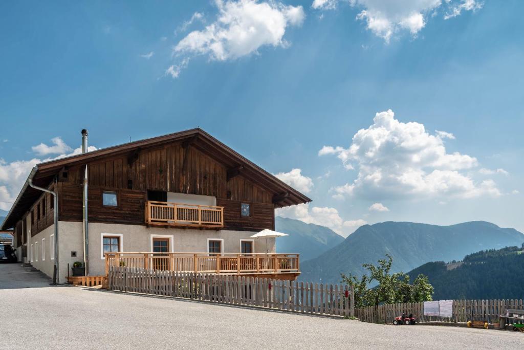 a large wooden house with a fence and mountains at Sparberhof Exklusive in Campo di Trens