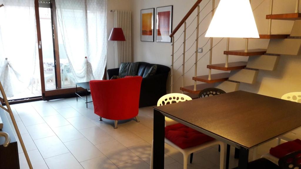 ein Wohnzimmer mit einem Tisch, Stühlen und einer Treppe in der Unterkunft Residence Lucia 2 in Grado