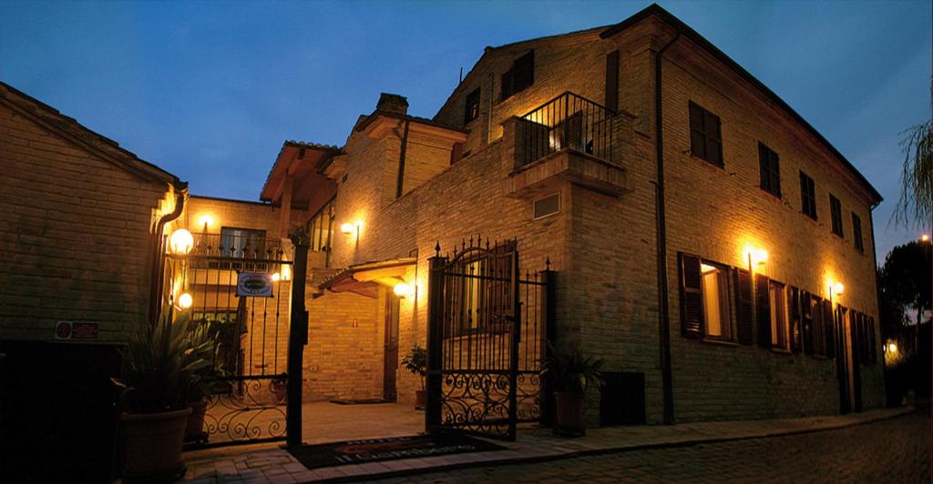 un grande edificio in mattoni con luci accese di notte di Hotel Ristorante Il Gambero a Porto SantʼElpidio