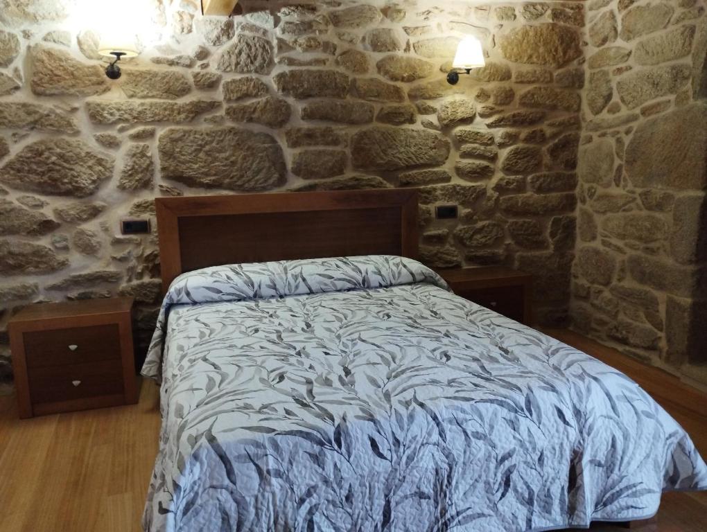 - une chambre avec un lit dans un mur en pierre dans l'établissement Casa San José, à Muros
