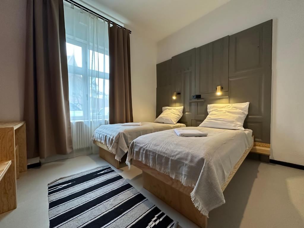 a bedroom with two beds and a large window at Schillinger-Berlin - dance, sleep, repeat! in Berlin
