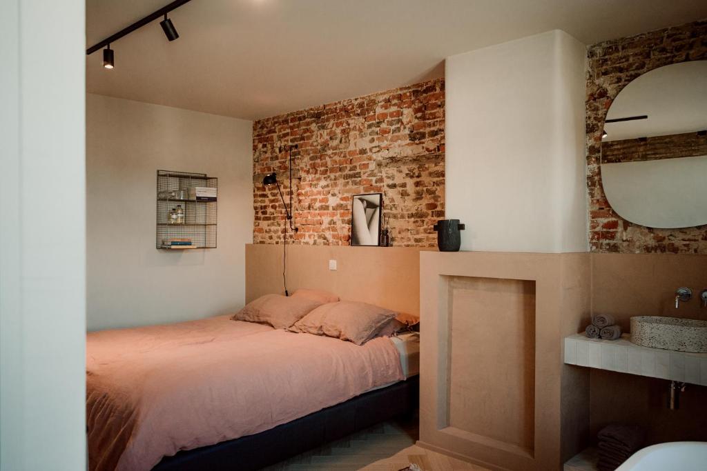 1 dormitorio con cama y pared de ladrillo en Plein 11, en Maarkedal
