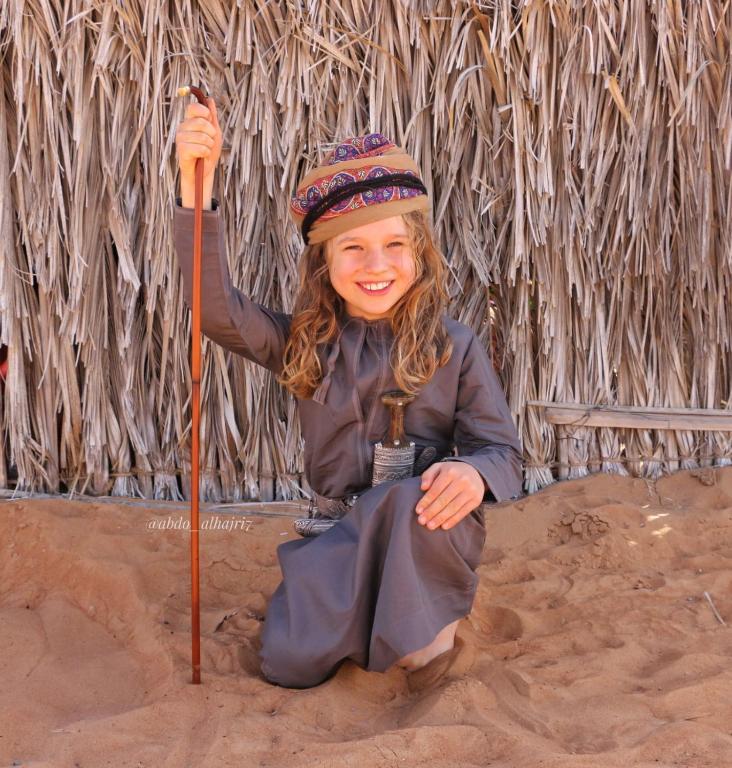 a little girl sitting in the sand holding a stick at Moon Light Camp in Bidiyah