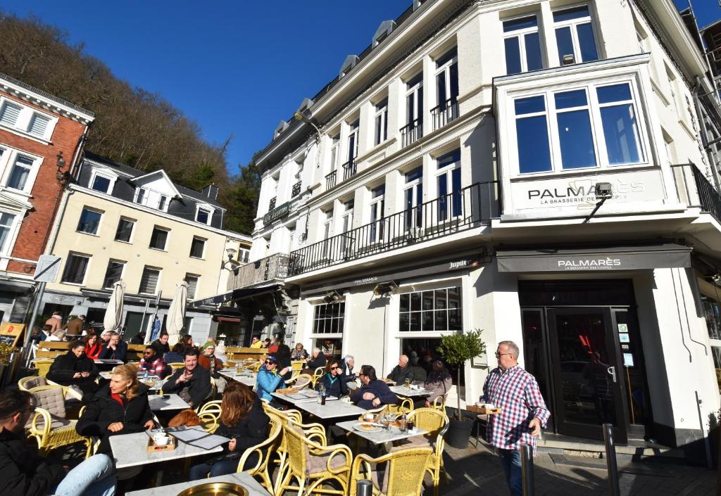 un groupe de personnes assis à des tables à l'extérieur d'un bâtiment dans l'établissement Luxury Spa Hotel - Automobile, à Spa