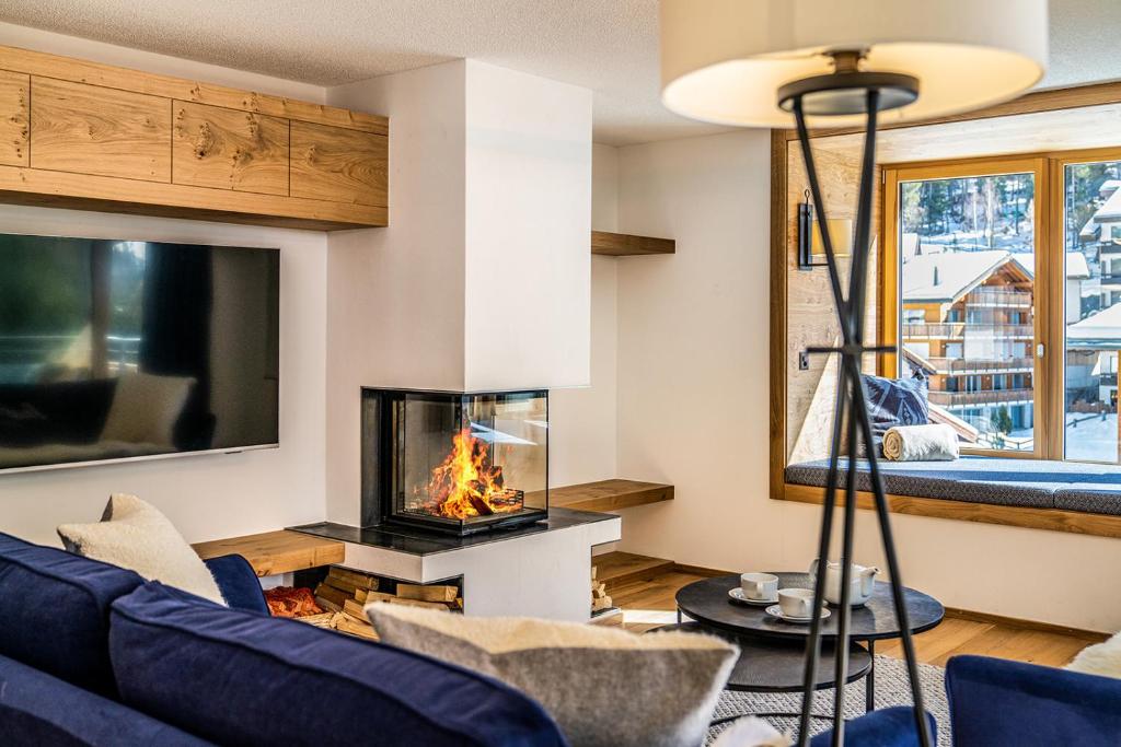 a living room with a fireplace and a blue couch at Riverside 2nd Floor South in Saas-Fee