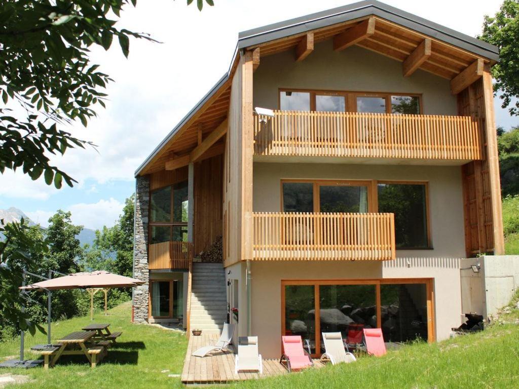 a house with a balcony and a table and chairs at Chalet le 1000 Thabor in Valmeinier