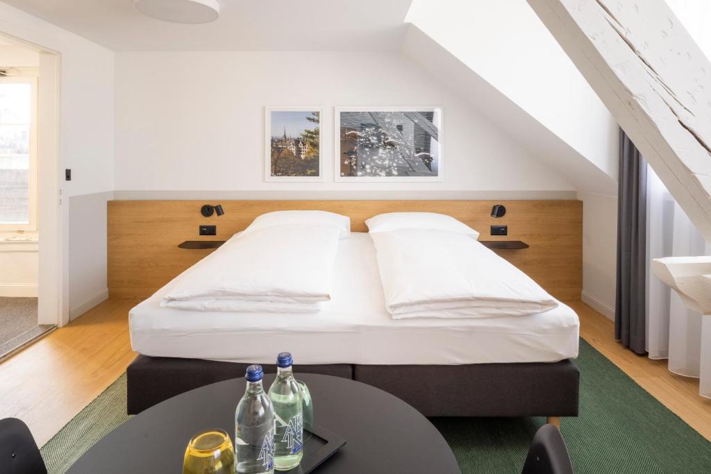 Un dormitorio con una cama y una mesa con botellas. en Fred Hotel Zürich Hauptbahnhof, en Zúrich