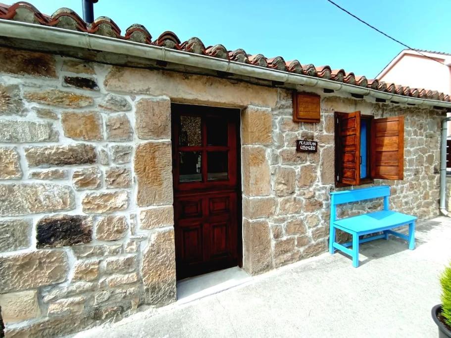 una casa de piedra con una puerta roja y un banco azul en Cabaña de Piedra en Picos de Europa en Arenas de Cabrales