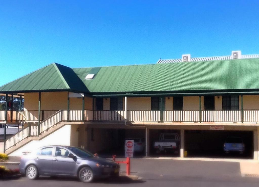 ein Auto, das vor einem Gebäude mit grünem Dach geparkt ist in der Unterkunft Town Square Motel in Orange