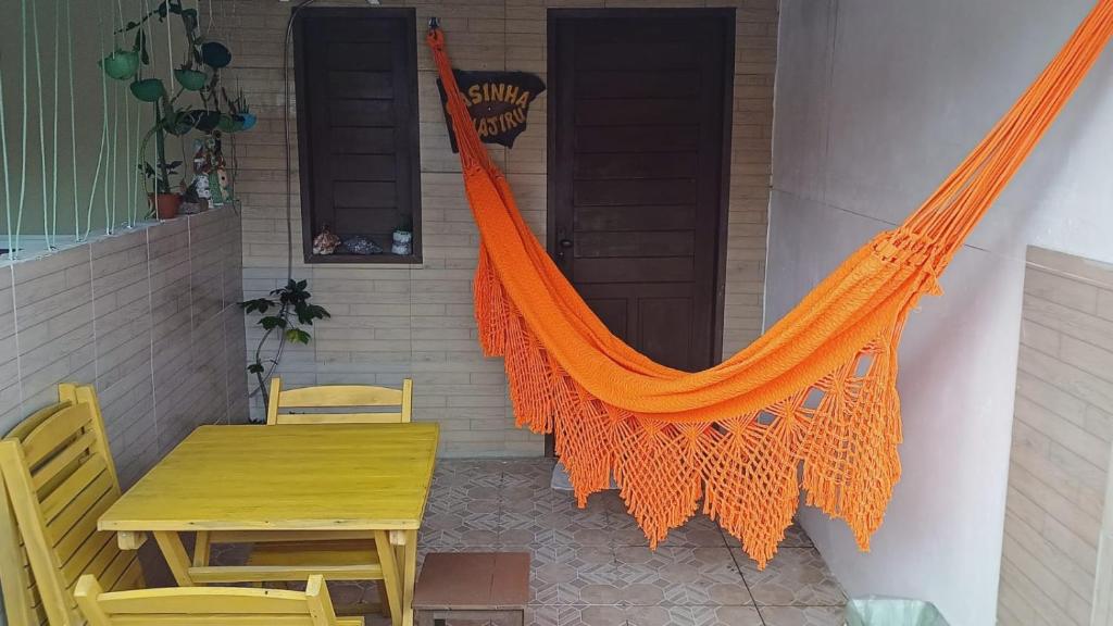una hamaca naranja colgada en el lateral de una casa en Casinha Guajiru, en Trairi