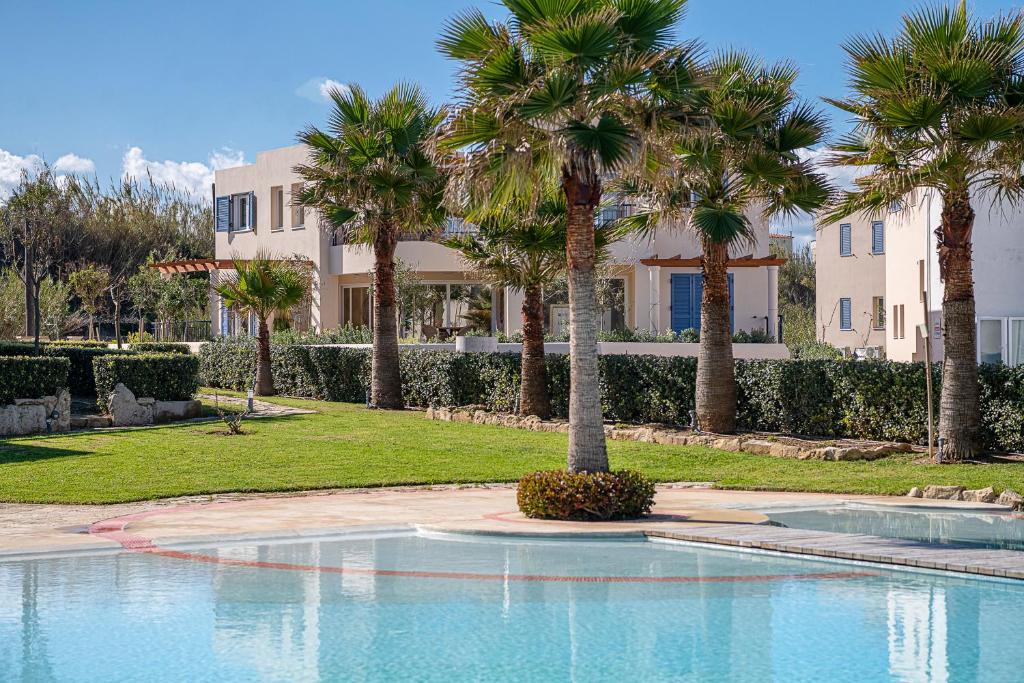 a swimming pool with palm trees in front of a building at Calmaliving Seaside apartments with pool in Gerani Chanion