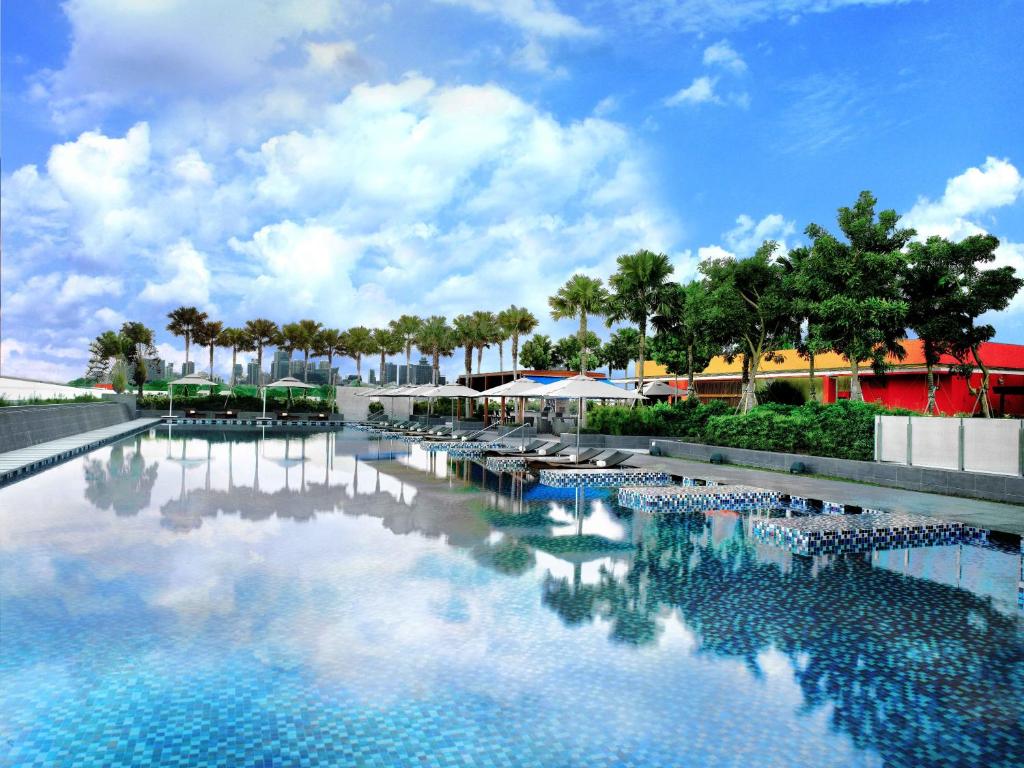 a pool of water with palm trees and a cloudy sky at One Farrer Hotel in Singapore