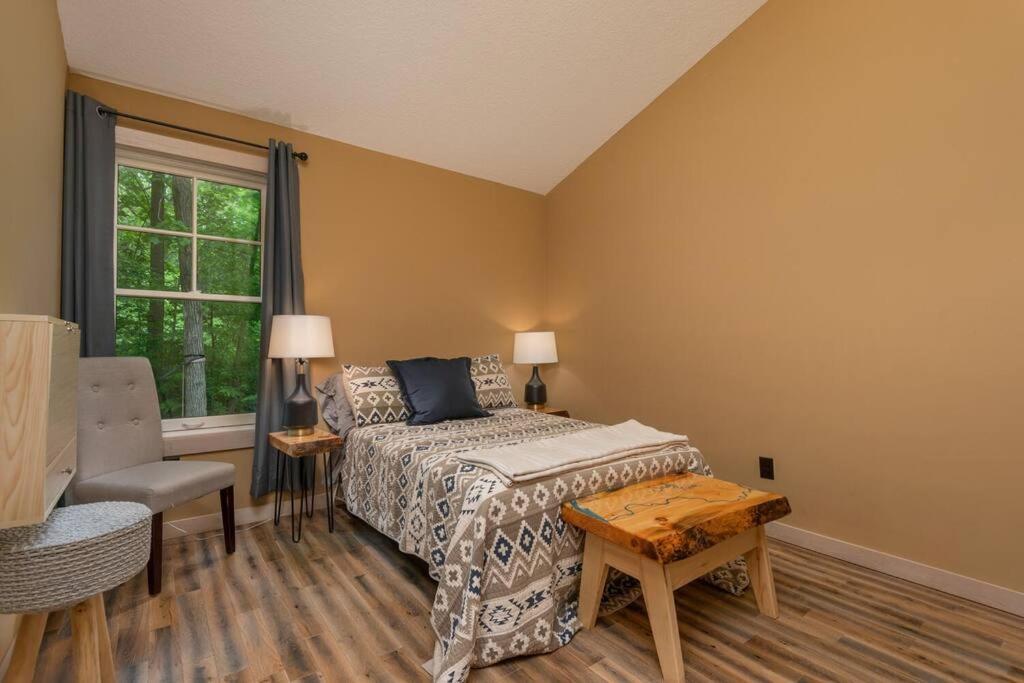 1 dormitorio con cama, mesa y ventana en Wilderness Meadows, en Pine City