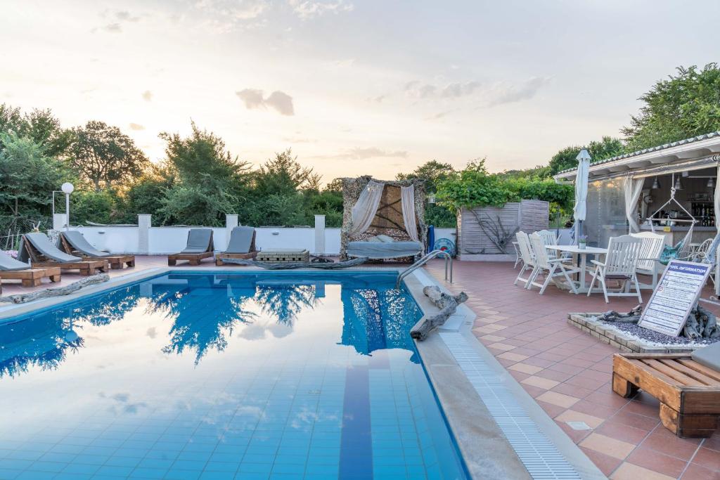 a swimming pool with chairs and a patio with a table at Villa Del Sol Corfu in Sidari