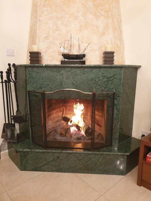 una chimenea verde con fuego en Kakopetria's Holiday House, en Kakopetria