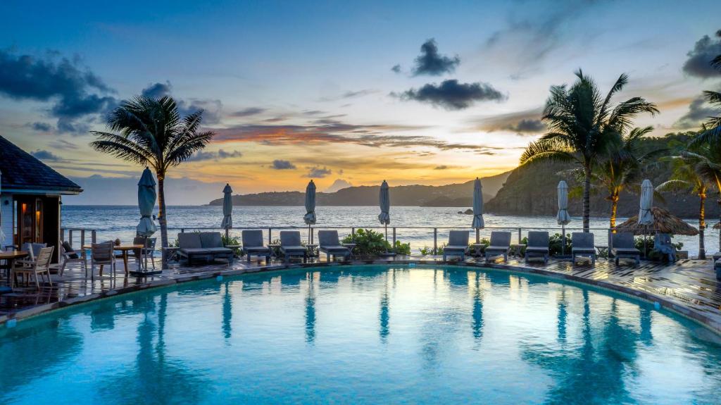 - une piscine avec des chaises et l'océan en arrière-plan dans l'établissement Hotel Manapany, à Gustavia