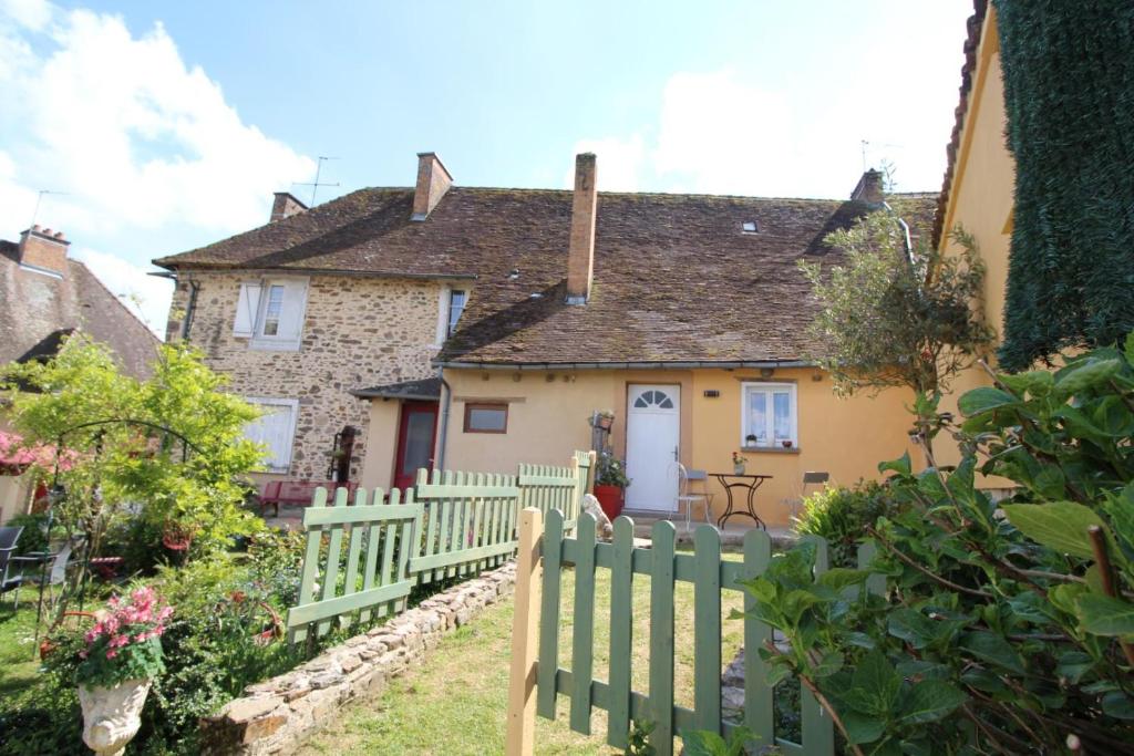 a house with a fence in front of it at La maison de marie in Saint-Germain-les-Belles