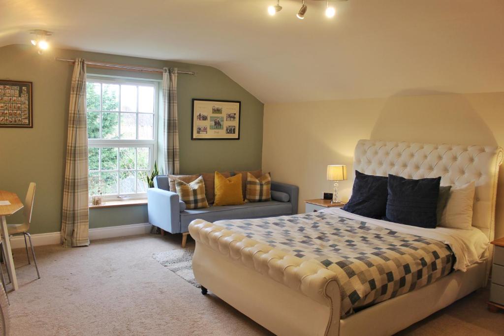 a bedroom with a bed and a couch and a window at The Ibex Inn in Newbury