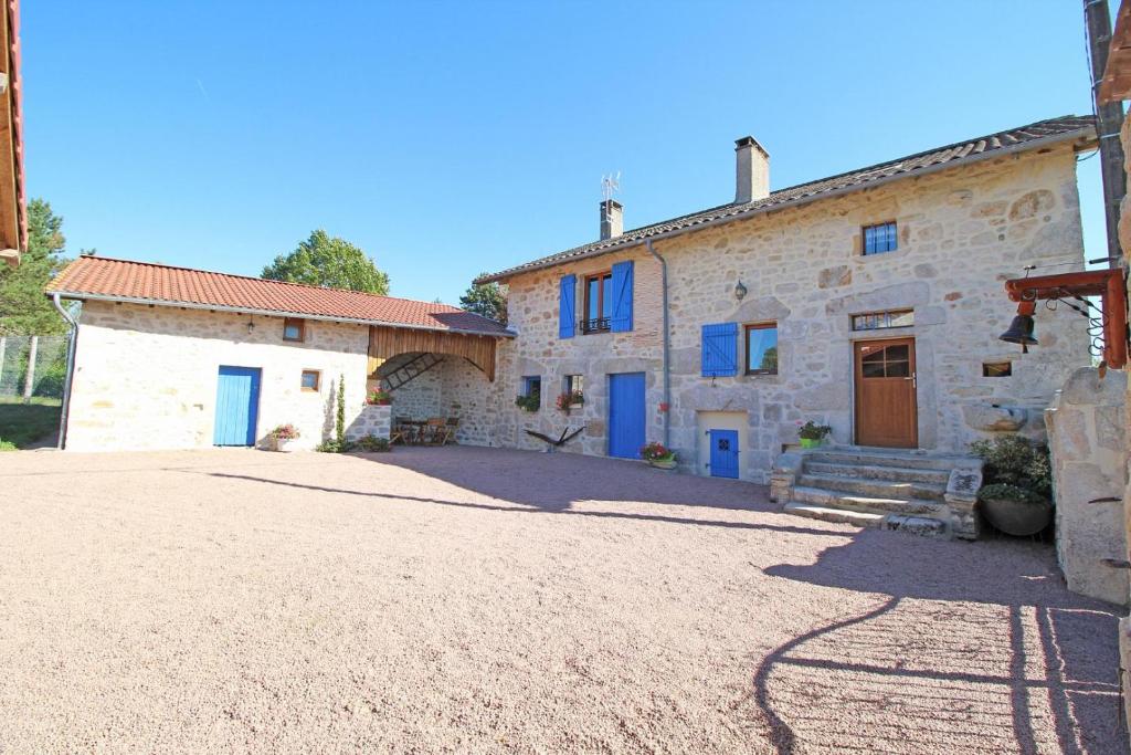 une grande maison en pierre avec des portes bleues et une allée. dans l'établissement Chez mimi, à Pensol