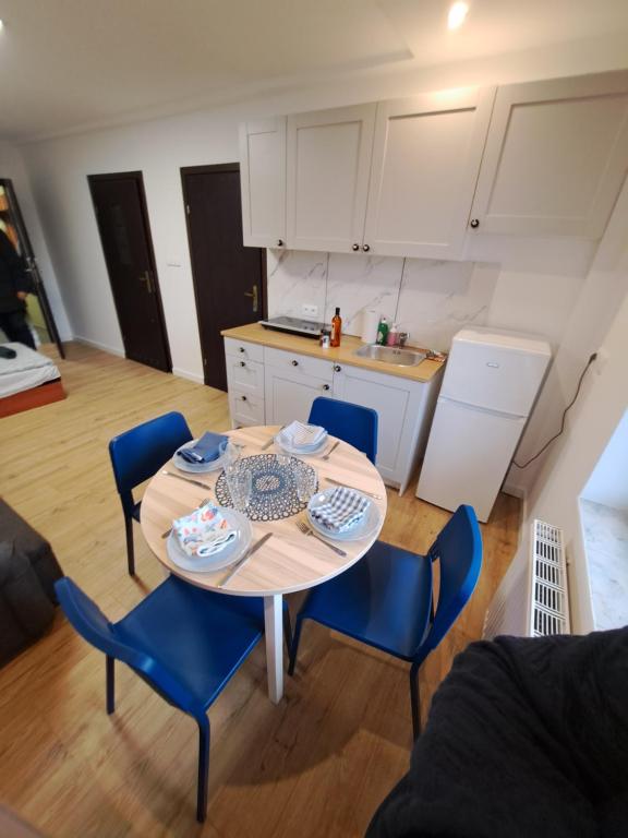 kuchnia i stół z niebieskimi krzesłami w pokoju w obiekcie Noclegi przy Browarnej w mieście Żyrardów