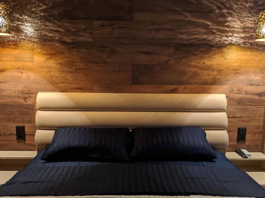 Bett in einem Zimmer mit einer Holzwand in der Unterkunft Новая, уютная квартира по ул. Grenoble 120/10 in Chişinău