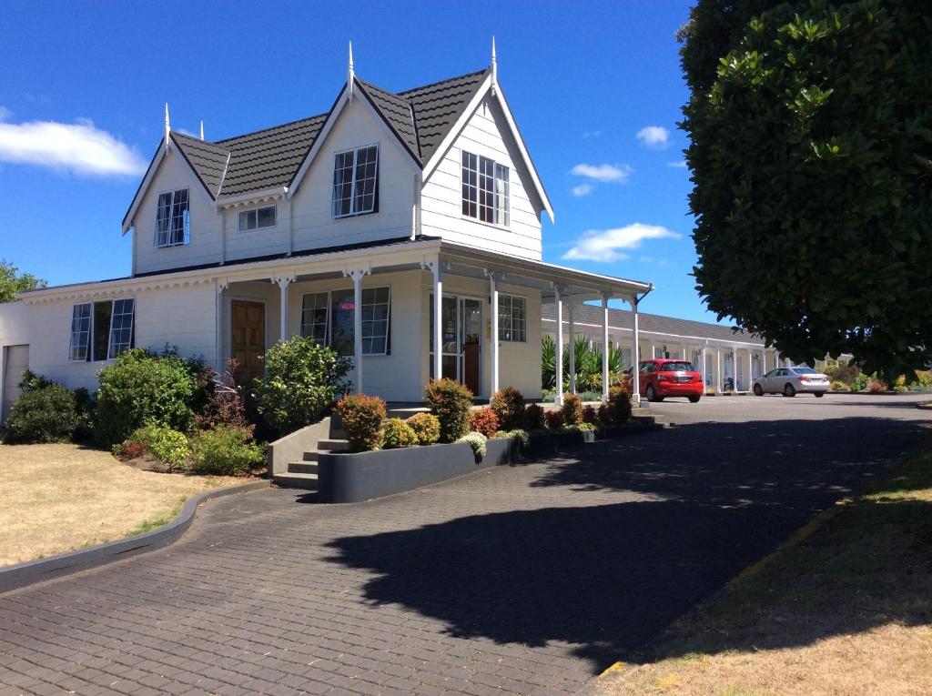 a white house with a car parked in front of it at Kings Court Motel in Whanganui