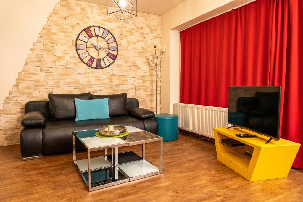 a living room with a black leather couch and a tv at Fewo Art City-Studio Kassel 1, modern, voll ausgestattet, zentrale Innenstadtlage, ruhiges Schlafzimmer, Balkon in Kassel