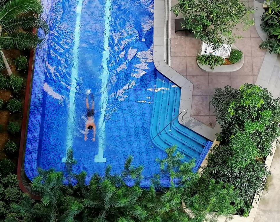 a person swimming in a large swimming pool at 2BR Pioneer Woodlands SM LIGHT by AwayHome Rentals in Manila