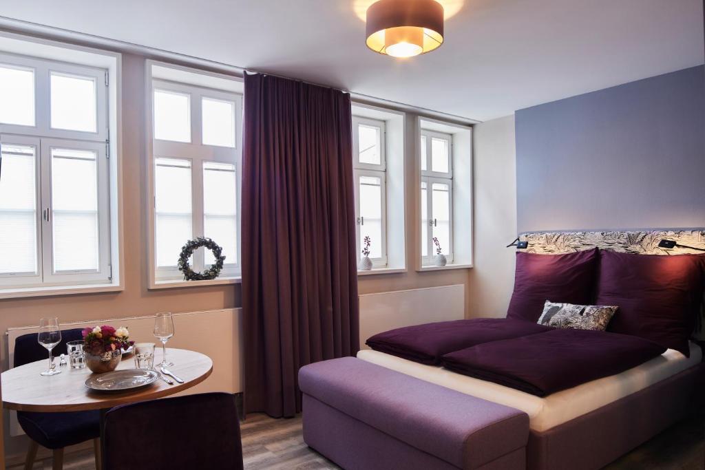 a bedroom with a bed and a table and windows at Fachwerk-Romantik am Dom in Fulda