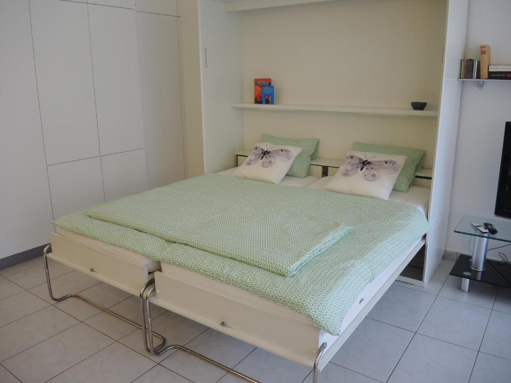 Schlafzimmer mit einem Bett mit grüner Bettwäsche und Kissen in der Unterkunft Sibylle in Locarno