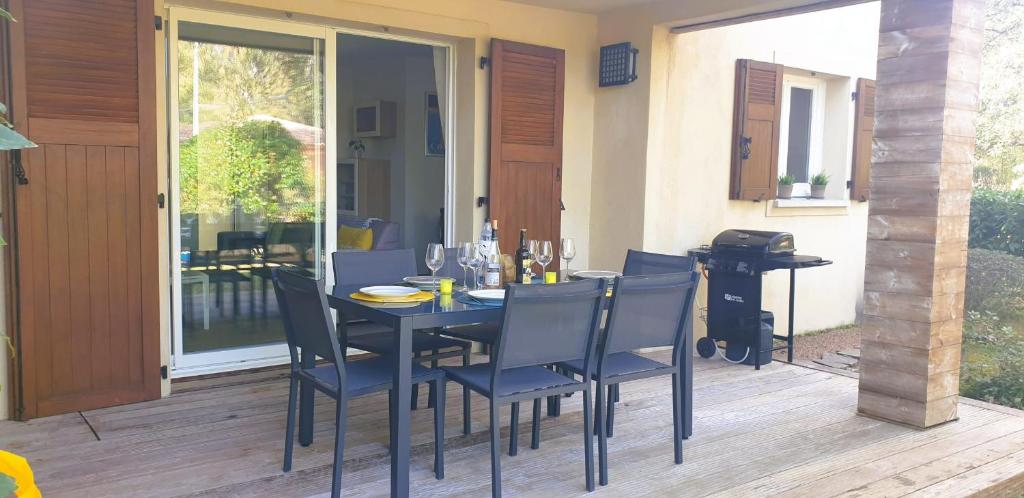 - une table à manger et des chaises sur une terrasse avec une porte en verre dans l'établissement Appartement Lena 6 pers piscine 500 m plage, à Sainte-Lucie de Porto-Vecchio