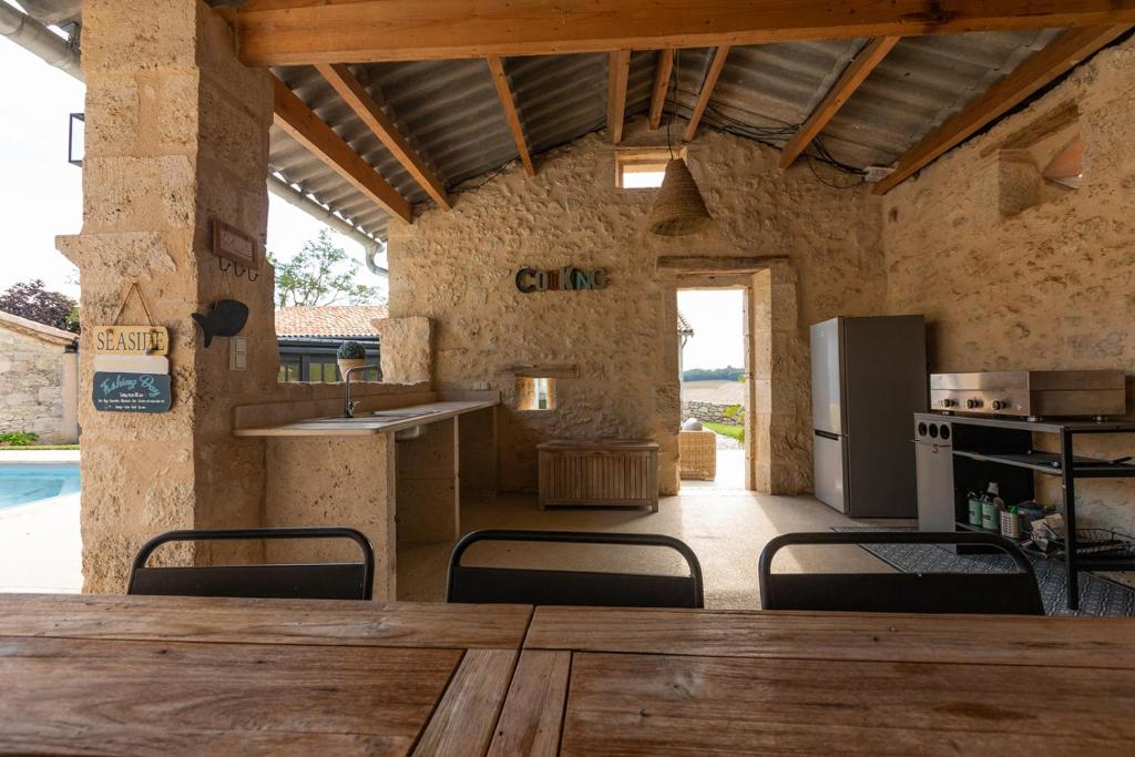 a kitchen with a table and chairs and a refrigerator at Mas des Coteaux - vue panoramique - piscine - babyfoot - pingpong - pétanque &amp; espace enfants à 1h de MONTAUBAN in Gramont