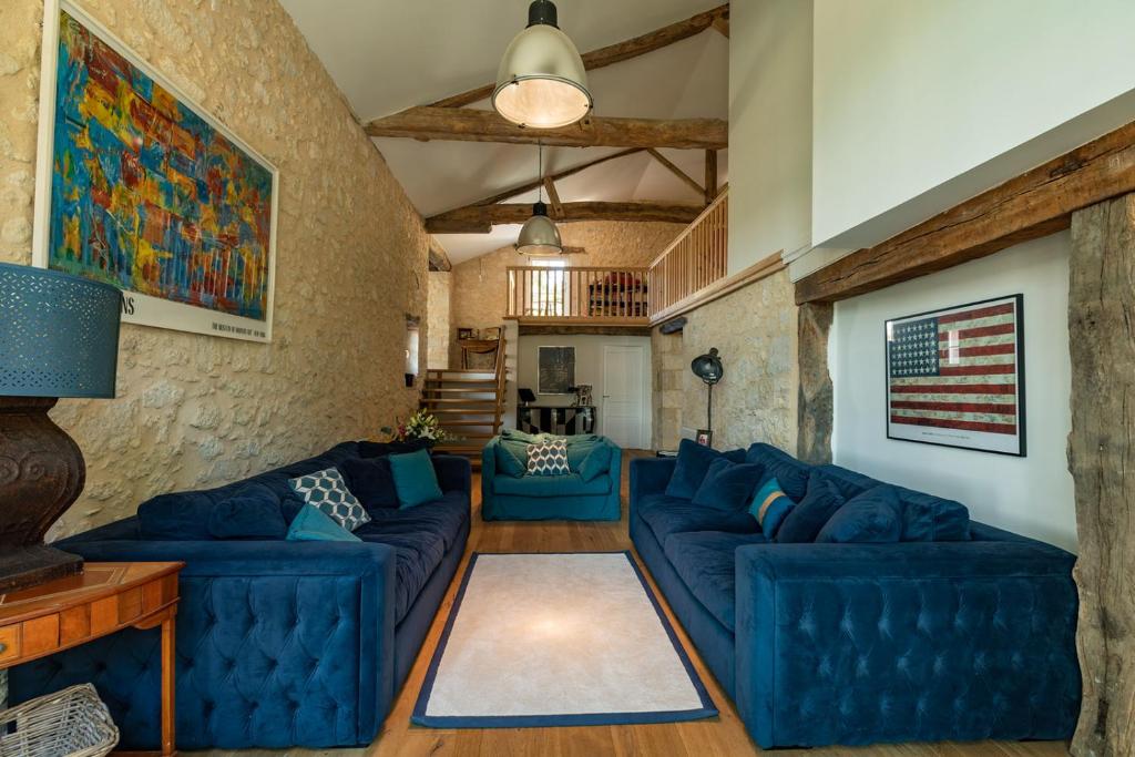 a living room with blue couches and a stone wall at Mas des Coteaux - vue panoramique - piscine - babyfoot - pingpong - pétanque &amp; espace enfants à 1h de MONTAUBAN in Gramont
