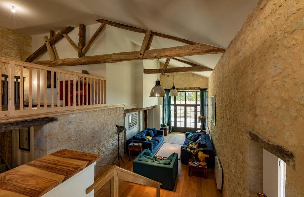 a living room with a large stone wall at Mas des Coteaux - vue panoramique - piscine - babyfoot - pingpong - pétanque &amp; espace enfants à 1h de MONTAUBAN in Gramont