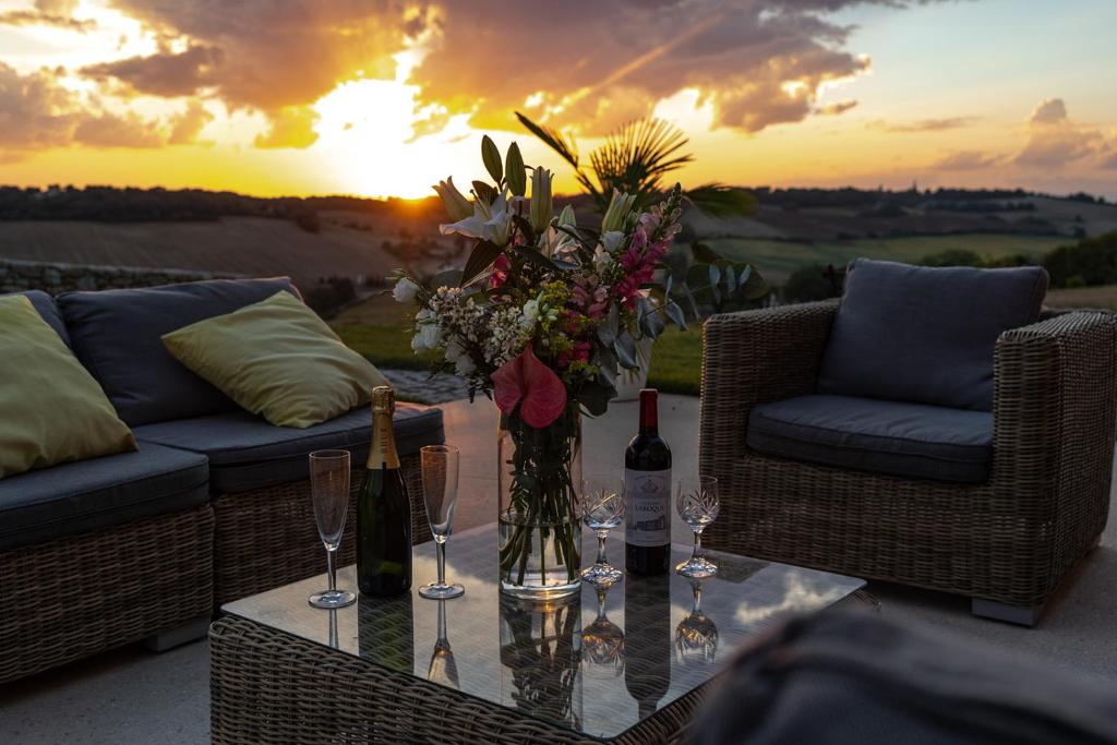 a table with wine glasses and a vase with flowers at Mas des Coteaux - vue panoramique - piscine - babyfoot - pingpong - pétanque &amp; espace enfants à 1h de MONTAUBAN in Gramont