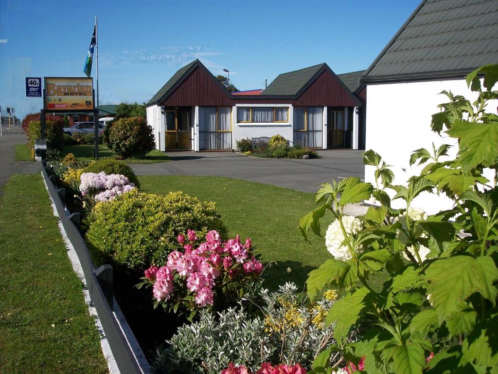 a garden with flowers and a house at Bavarian Motel in Invercargill
