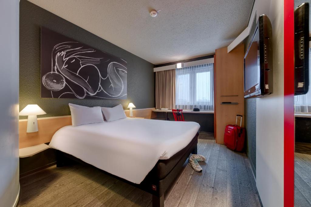 a hotel room with a large bed and a tv at ibis München Parkstadt Schwabing in Munich