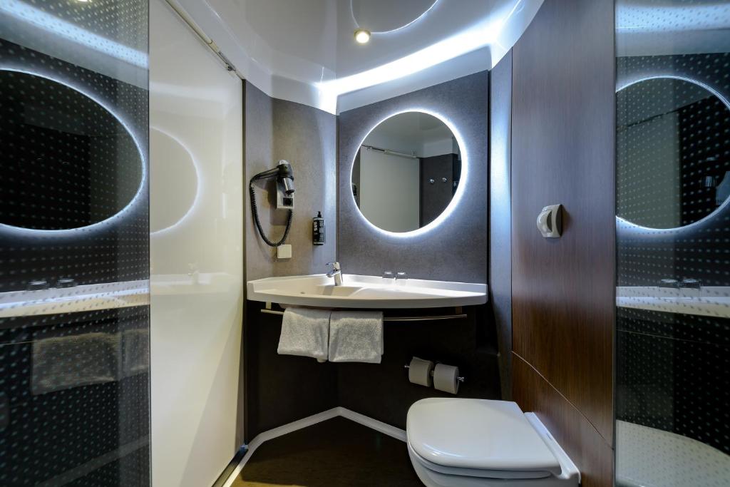 a bathroom with a toilet and a sink and a mirror at ibis München Parkstadt Schwabing in Munich