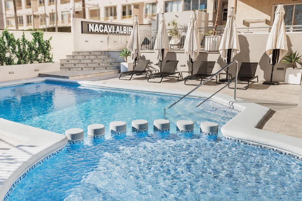 uma grande piscina com cadeiras e guarda-sóis em Nacavi Albir Aparthotel em Albir