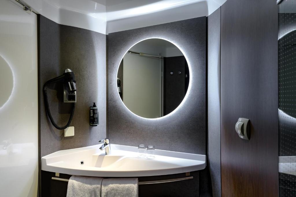 a bathroom with a sink and a mirror at ibis München Parkstadt Schwabing in Munich