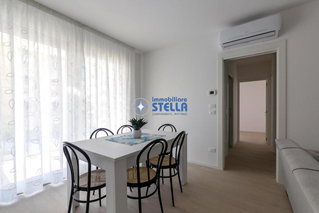 a white dining room with a table and chairs at Condominio Medusa in Lido di Jesolo