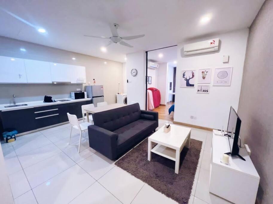 ein Wohnzimmer mit einem schwarzen Sofa und einer Küche in der Unterkunft [Promo] Connected Train 2 Bedroom (ABOVE MALL) 28 in Kuala Lumpur