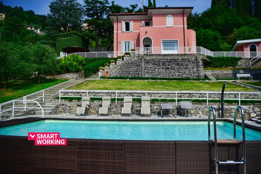 a swimming pool in front of a pink house at Villa Perledina by Wonderful Italy in Perledo
