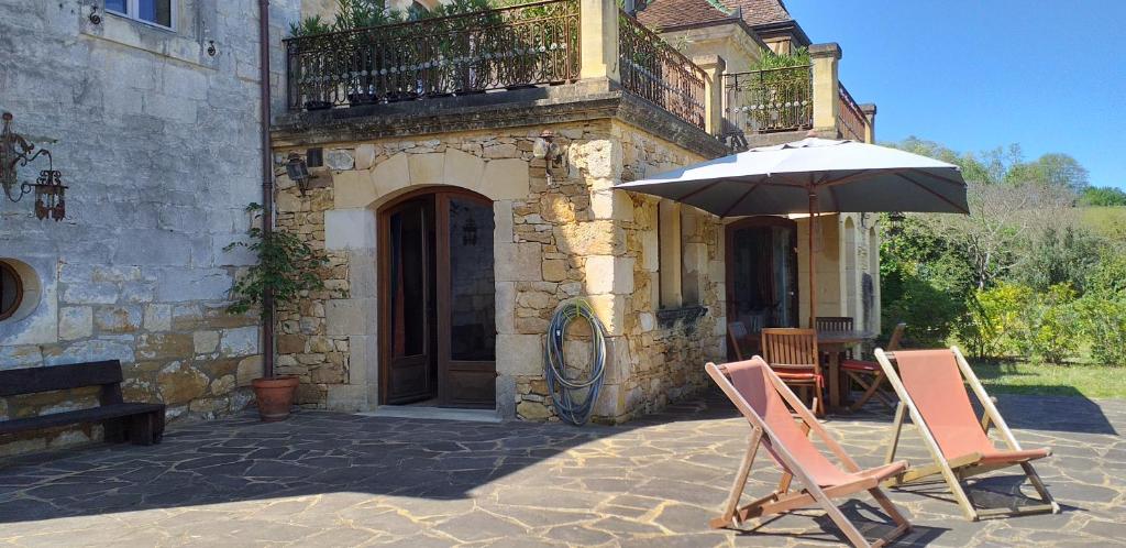 dwa krzesła i parasol przed budynkiem w obiekcie Domaine du Fraysse Le Cèdre un havre de paix w mieście Saint-Cybranet